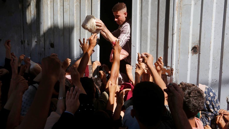 Hundreds of Palestinians crowd bakery in Gaza to buy bread amid acute food shortage